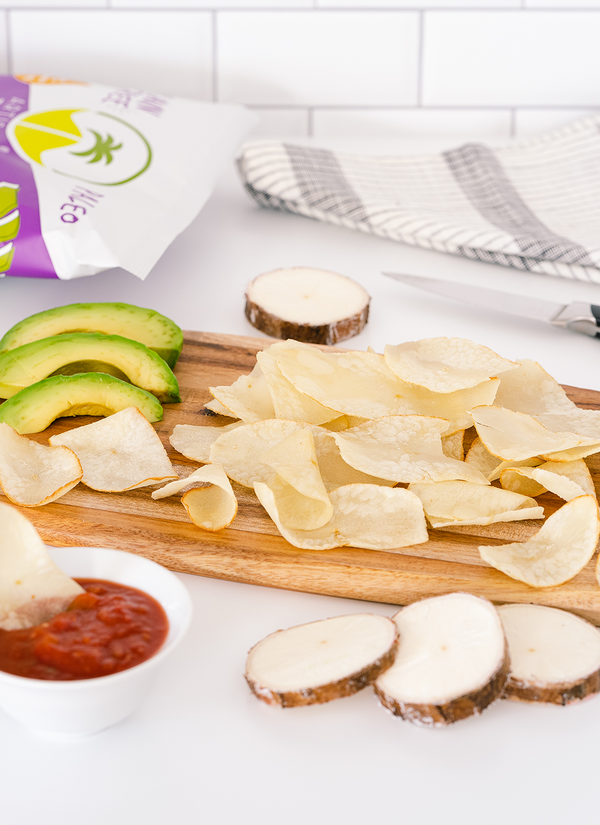 Cutting board with Artisan Tropic's 4.5 oz Sea Salt Cassava Strips, sliced avocados and red salsa